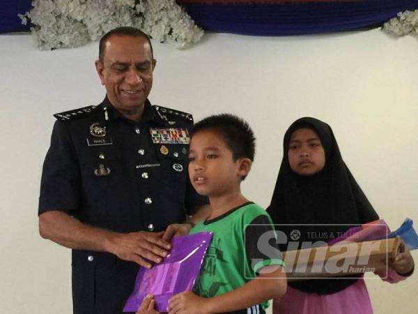 Mohd Khalil menyampaikan sumbangan kepada seorang pelajar SK Polis Kem, Kulai hari ini.