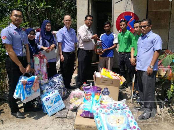 Rizuwan (empat, kanan) menerima sumbangan pelbagai pihak yang berkunjung ke rumahnya di Kampung Ladang, hari ini.
