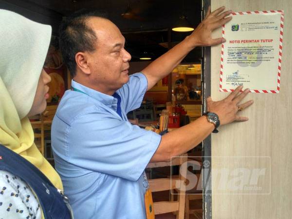 Pegawai Kesihatan Persekitaran MPSJ, Nordin Harun menampal notis penutupan pada pintu hadapan premis terbabit