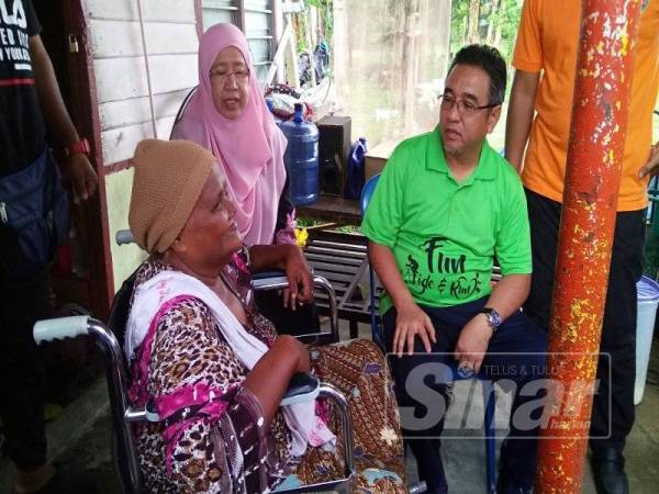 Adly (kanan) dan Rusnah menyantuni Sokyah ketika menziarahi keluarga berkenaan di Kampung Paya Rumput Hilir di sini, hari ini.