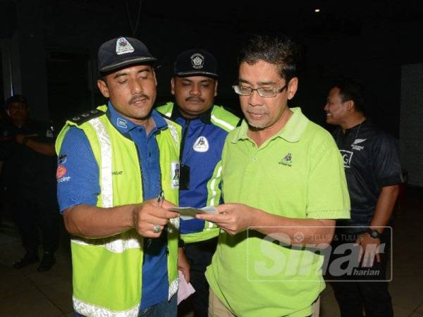 Juhari (kanan) memeriksa dokumen premis yang beroperasi tanpa kebenaran.