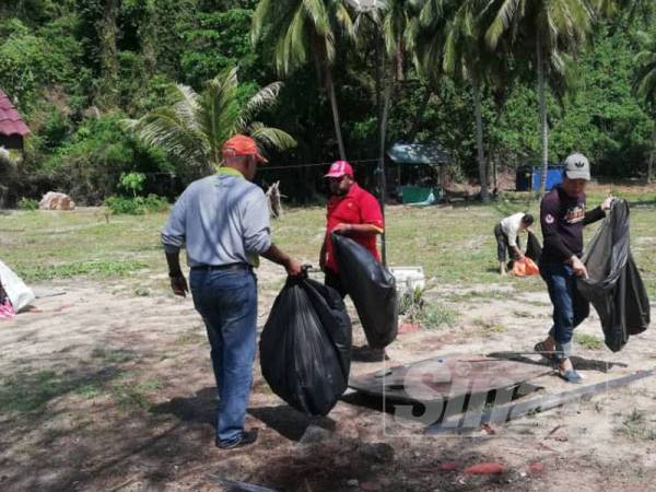 Mohd Ridzwan melakukan gotong-royong membersihkan Pulau Bidan, semalam. 
