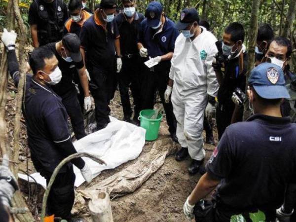 Anggota forensik Polis DiRaja Malaysia memeriksa jenazah yang ditemui di kubur yang tidak ditanda berhampiran Wang Kelian di puncak Bukit Wang Burma di Wang Kelian yang terletak di sempadan Malaysia-Thailand. - Foto fail AP