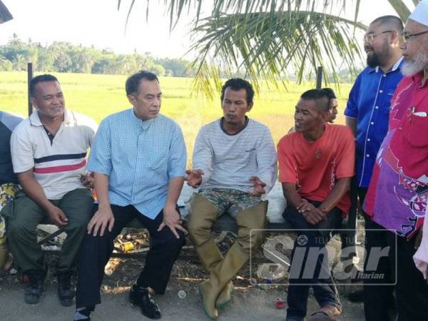 Husam (tiga, kiri) mendengar permasalahan pesawah di bendang Kampung Wakaf, semalam.
