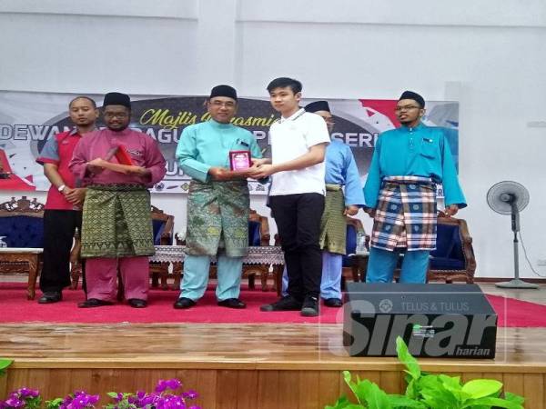 Adly (tengah) ketika menyampaikan cenderamata kepada salah seorang pelajar cemerlang dalam Dun Serkam ketika menyempurnakan perasmian Dewan Serbanguna DUN Serkam, di sini, hari ini.