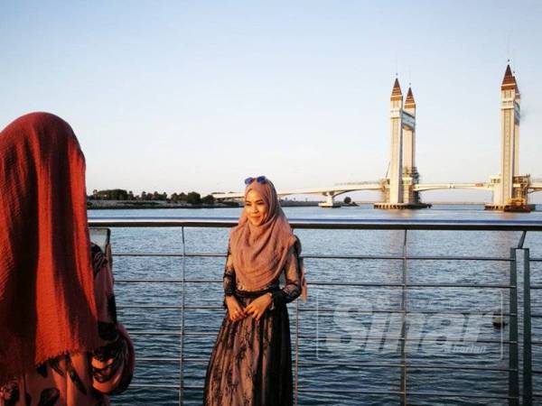 Nur Jannah (kanan) mengabadikan gambar kenangan yang dirakam kakaknya, Nurul Syahida.