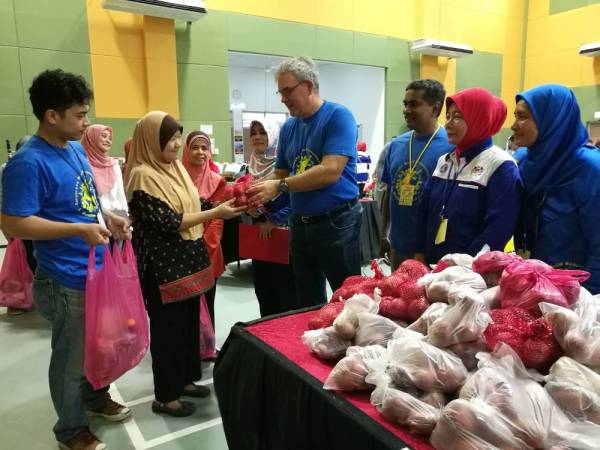 Michael (empat dari kanan) menyampaikan bawang di salah satu kaunter bantuan kepada Norizan Rezuwan, 58 dari Desa Rakyat di sini, hari ini.