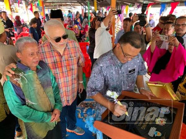 Isham menandatangani plag sebagai gimik perasmian Pasar Tani Terapung Kota Pengkalan Datu di sini hari ini.
