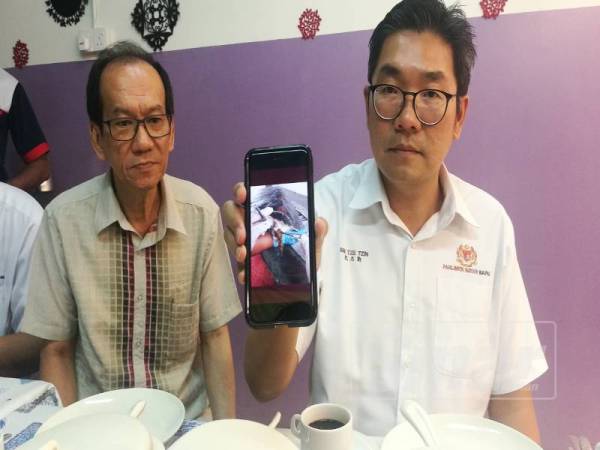 Tze Tzin (kanan) menunjukkan gambar penyu agar yang diselamatkan Jabatan Perikanan selepas didapati saluran rektumnya tersumbat dengan sisa plastik.
