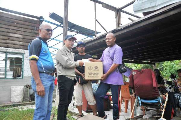 Abdul Yunus(dua dari kiri) menyerahkan sumbangan kepada wakil keluarga yang terjejas rumah akibat ribut di Kuala Kurau hari ini.