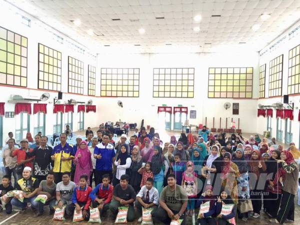 Baharudin (enam berdiri hadapan) bergambar bersama pelajar dan ibu bapa yang menerima sumbangan daripadanya.