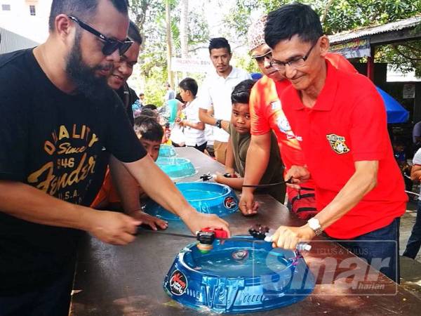 Mustaffa (kanan) tidak kekok bermain gasing moden atau lebih dikenali sebagai beyblade bersama peserta yang lebih muda.