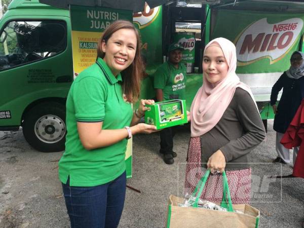 Natasya (kanan) menerima replika lori milo yang disampaikan oleh Maria Murni di rumahnya di Bukit Istana di sini, hari ini.