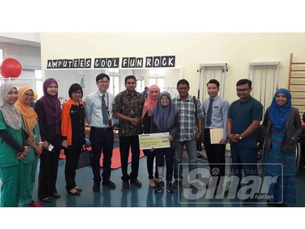 Elia Nurul Syahida (lima, kanan) ketika menerima replika cek faedah hilang upaya kekal yang disampaikan Santhara.