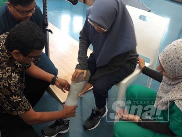 Santhara (kiri) membantu memakaikan kaki palsu kepada Elia Nurul Syahida di Pusat Pusat Rehabilitasi Perkeso Tun Abdul Razak, Melaka (PRPTAR) di sini hari ini.
