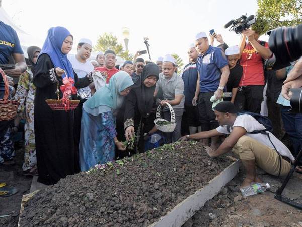 Datin Seri Rosbi Shahbudin (tengah) menabur bunga mawar di atas pusara suaminya Allahyarham Datuk Seri Abu Hassan Din Al Hafiz setelah selamat dikebumikan di Tanah Perkuburan Raudatul Sakinah hari ini.- Foto Bernama
