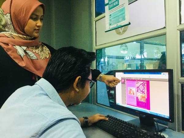 
Seorang pelanggan (kanan) dibantu oleh kakitangan UPrint memilih reka bentuk Sampul Duit Raya Personalize di Shah Alam baru-baru ini.