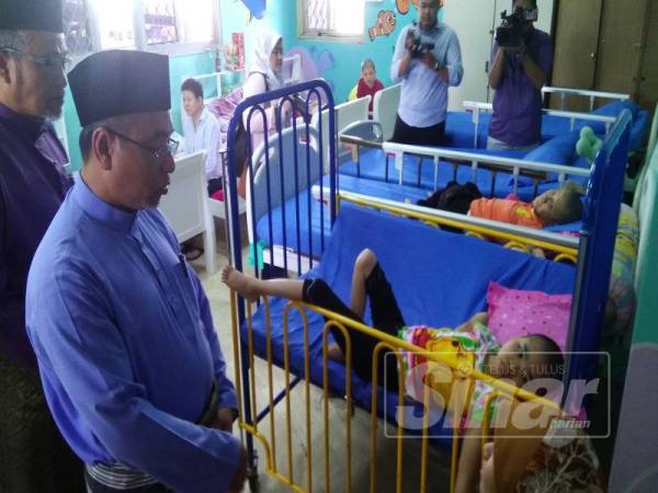 Adly (dua,kiri) ketika melawat salah seorang penghuni di Pusat Penjagaan Kanak-kanak Terencat Akal di Bukit Baru di sini, hari ini.
