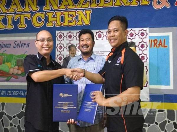  Hamedi (kiri) dan Mohammad Yusri bertukar dokumen perjanjian persefahaman sambil disaksikan Megat D. Shariman (tengah) di sini malam tadi.