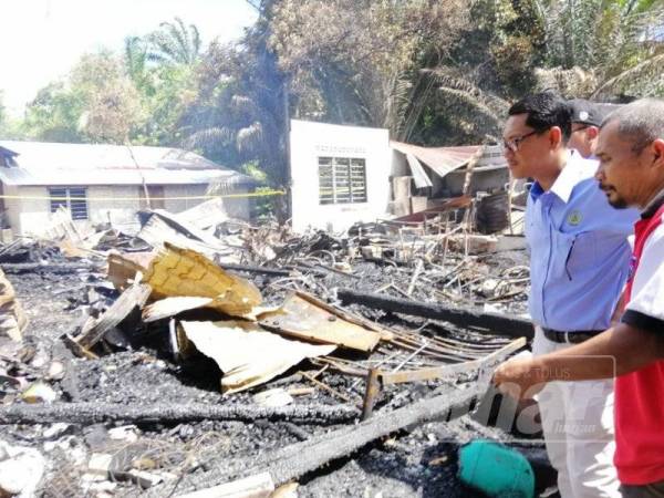 Norhisham (kanan) menunjukkan keadaan rumahnya yang terbakar ketika dikunjungi Ahmad Faizal.