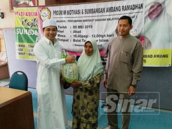 Adam (kiri) menyerahkan sumbangan beras kepada salah seorang penerima asnaf di Balai Tasawwur Islam, Bagan Serai hari ini.