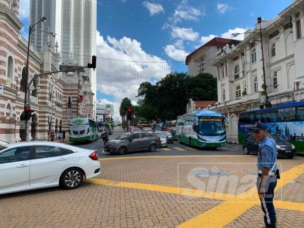 Anggota trafik warden DBKL mengawal lalu lintas di persimpangan Lebuh Pasar.