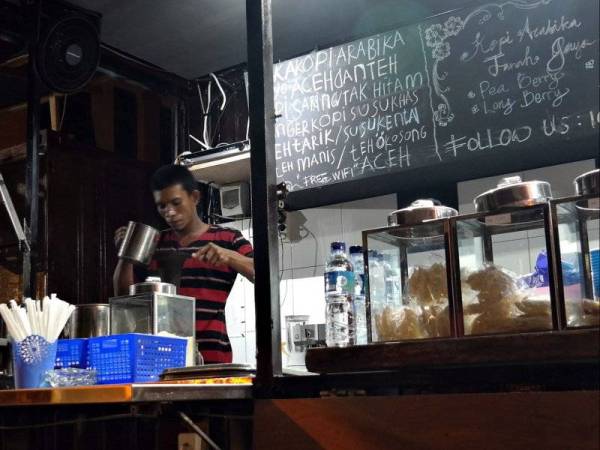 Seorang peniaga warung kopi di Banda Aceh menyiapkan pesanan pelanggannya.
