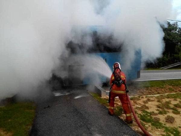 Anggota bomba bertungkus-lumus memadam kebakaran bas kilang di Jalan Sepri Rembau, di sini pagi ini. - Foto Ihsan bomba