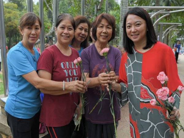 Timbalan Menteri Pembangunan Wanita, Keluarga dan Masyarakat yang juga Anggota Parlimen Segambut, Hannah Yeoh (kanan) memberikan Bunga Teluki kepada penduduk setempat pada tinjauan mesra sempena Hari Ibu di Taman Tasik Manjalara hari ini. - Foto Bernama