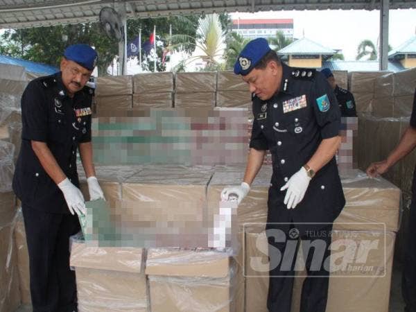 Paul (kanan) bersama Pegawai PPM W2 Muar, Deputi Superintendan Nordin Osman menunjukkan karton rokok yang disimpan dalam sebuah kotak.
