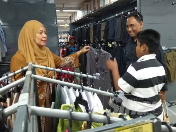 Mohd Firdaus memilih baju raya pilihannya ketika majlis tersebut di Pasar raya Econsave Bercham, di sini, baru-baru ini. 