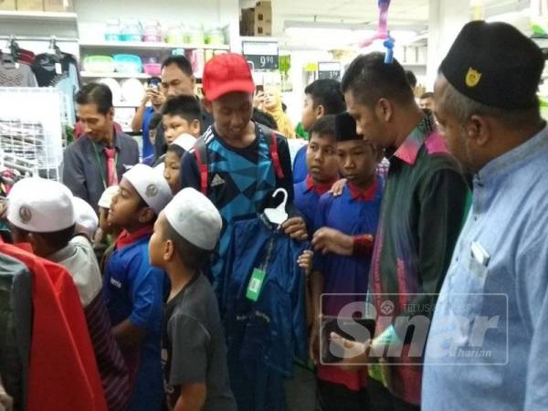 Mohd Syahrizal (dua, kanan) melihat anak-anak daripada Pertubuhan Badan Kebajikan Anak-anak Yatim Darussalam memilih pakaian. 