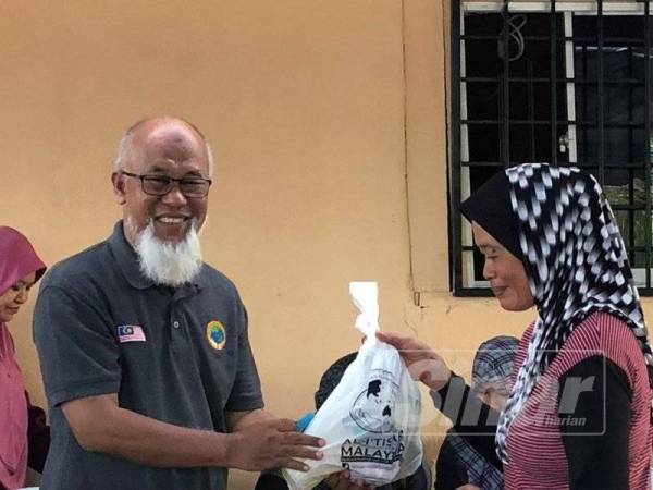 Mohd Shah (kiri) menyampaikan sumbangan kepada penerima di Program Iftar Nelayan Kuala Langat bersama Al-I’tisam di Jeti Kampung Kelanang, Banting semalam.
