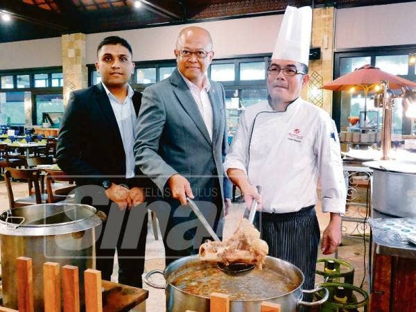 Pengurus Besar, Isaaz Ishak Yunus (tengah) dan Sous Cef, Ahmad Rosnie Mohamed Nor (kanan) menunjukkan salah satu menu yang menjadi tarikan di restoran itu.
