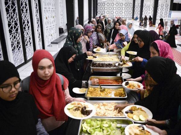 Para jemaah wanita sabar menunggu giliran untuk mengambil hidangan nasi beriani yang disediakan selepas selesai menunaikan solat Maghrib di Masjid Negara. Sempena Ramadan, pihak pengurusan Masjid Negara memperuntukan juadah berbuka puasa secara percuma untuk 1,500 jemaah setiap hari sepanjang bulan ini. Foto: Bernama