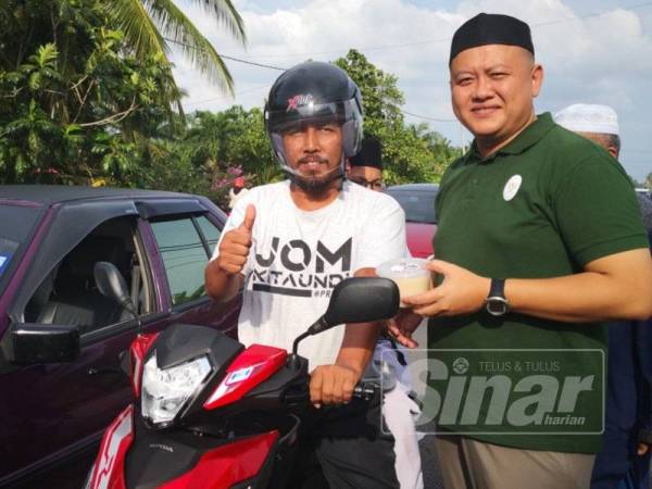 Rizam (kanan) bergambar bersama penduduk pada Program Penyerahan Bubur Lambuk di hadapan Pejabat ADUN Sungai Air Tawar di sini.