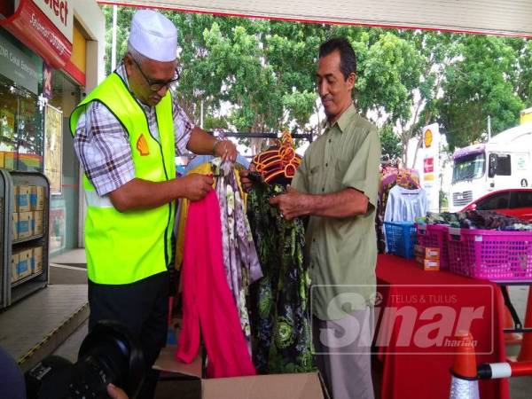 Zulkifly melihat pakaian yang diberikan oleh Md Yani (kanan) di stesen minyak itu.