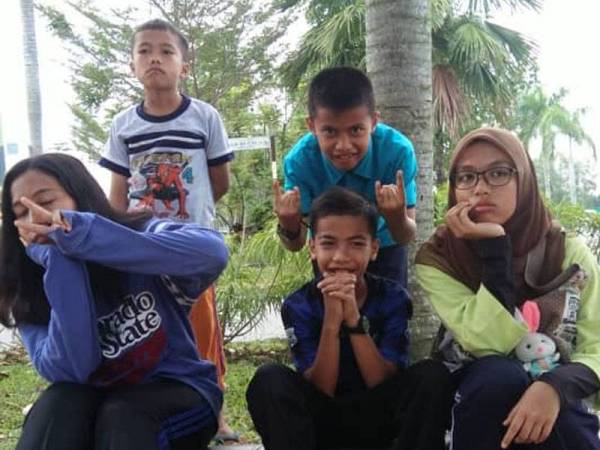 Zahiruddin (kiri, berdiri) di samping kakak dan abangnya.
