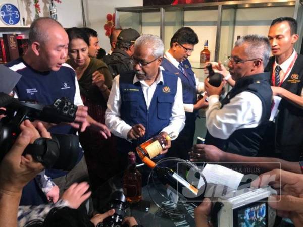 Sivanesan (tengah) melakukan pemeriksaan minuman alkohol bersama Jabatan Kesihatan Negeri di Bercham hari ini.