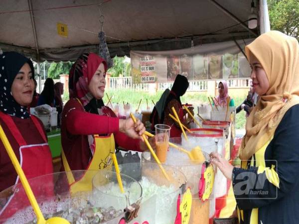 Nazarul Azma (tengah) menyediakan air untuk pelanggannya di Bazar Ramadan Dataran Peladang, Kuala Krai.
