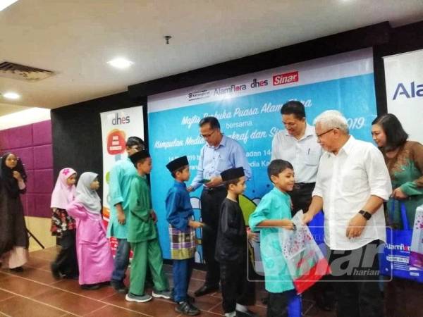 Mohd Zain (tiga dari kanan) dan Hussamuddin (kanan) menyampaikan sumbangan duit raya dan cenderamata kepada anak-anak yang diraikan.