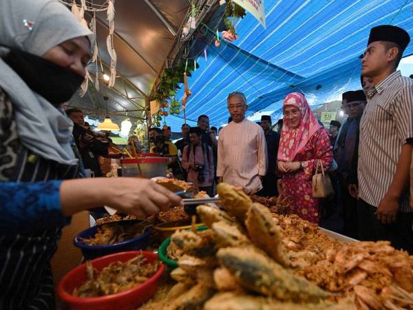 Yang di-Pertuan Agong Al-Sultan Abdullah Ri'ayatuddin Al-Mustafa Billah Shah dan Raja Permaisuri Agong Tunku Azizah Aminah Maimunah Iskandariah tertarik dengan juadah yang dijual peniaga Bazar Ramadan Taman Kerang hari ini. - Foto Bernama