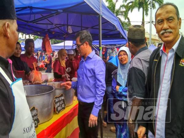 Chee Leong (dua, kanan) ditemani Rushidi (kanan) membuat lawatan serta mengagihkan apron kepada peniaga bazar pada program itu.