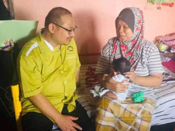 Yunos (kiri) beramah mesra bersama salah seorang penerima bantuan pada program berkenaan.
