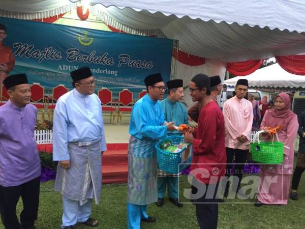 Eddin Syazlee (dua, kiri) memerhati Ahmad Faizal (tiga, kiri) menyampaikan sumbangan kepada asnaf pada program berbuka puasa di Kampung Batu Melintang, hari ini.