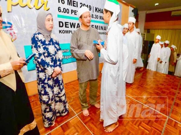 Mohd Hizamri menyampaikan duit raya kepada pelajar tahfiz Majlis Iftar Ramadan JPNP di Kompleks Sri Dagangan Indera Mahkota, semalam.