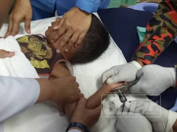 Anggota bomba membantu memotong mata kail yang tercucuk di tapai tangan seorang kanak-kanak lelaki berusia 4 tahun di bahagian kecemasan Hospital Tumpat hari ini.