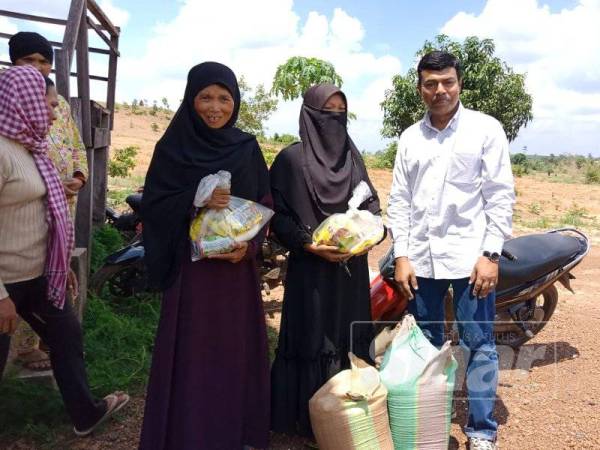 Mustapha (kanan) bersama Zainab Ali (dua dari kiri) dan Khatijah Mail (kiri sekali) yang menerima bantuan beras bagi bantuan fakir miskin sempena Ramadan.
