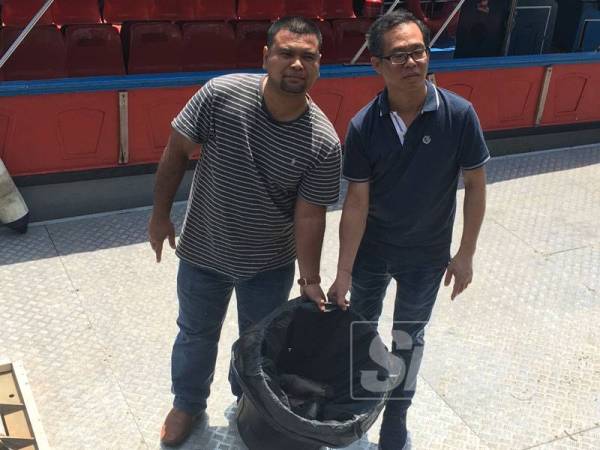 Azlan dan Chee Leong menunjukkan bakul berisi bangkai ikan