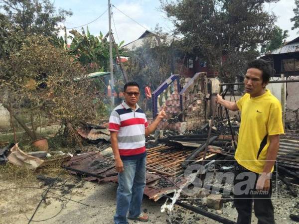 Sharifuddin (kiri) dan adiknya Khairul Anwar menunjukkan rumah pusaka peninggalan arwah bapa mereka yang musnah terbakar.